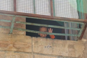a little Palestinian boy waving from an abandoned flat in the ghost town